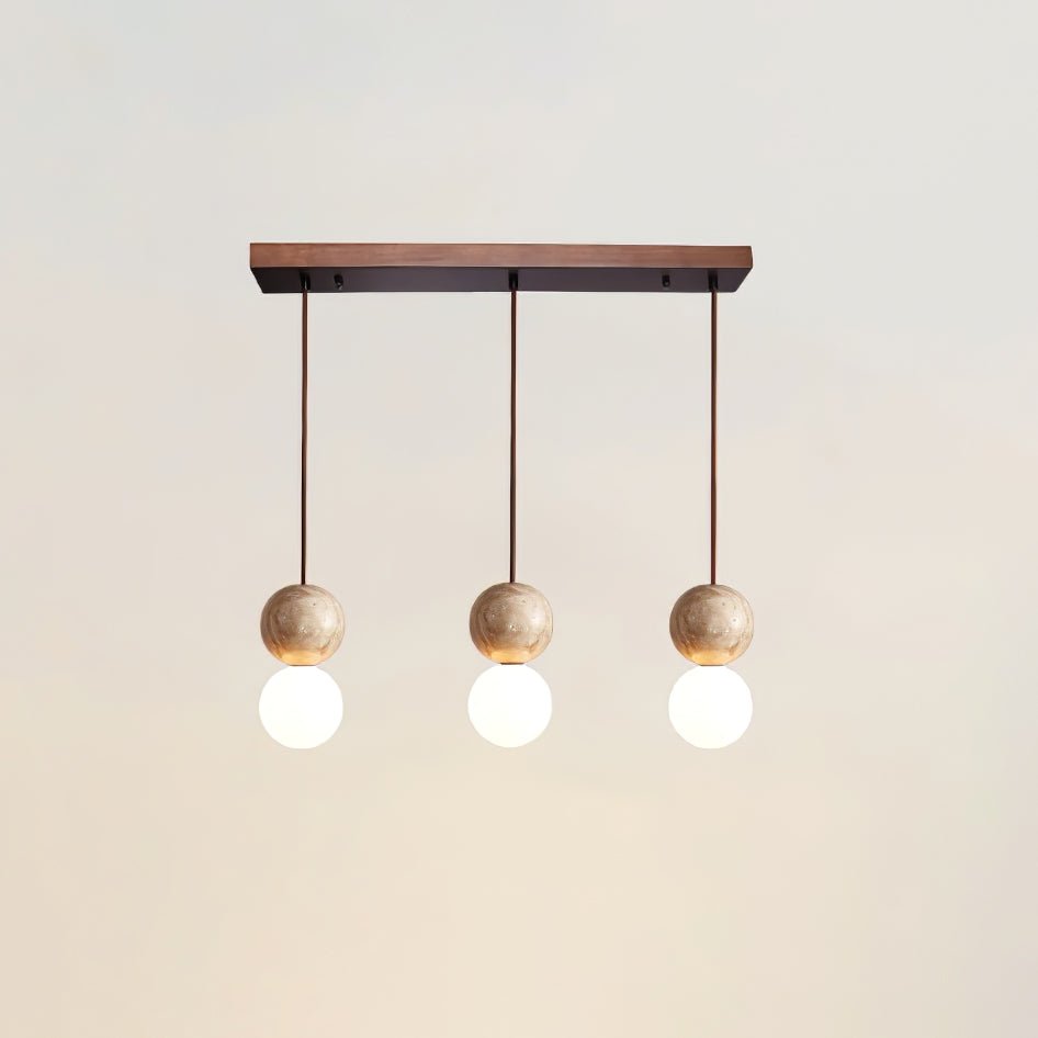 Three travertine spheres hang in a row from a long canopy on this Clérachic pendant, studio shot on white.