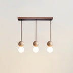 Three travertine spheres hang in a row from a long canopy on this Clérachic pendant, studio shot on white.