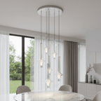 Clérachic pendants at staggered drop heights hang from a round ceiling plate beside a floor-to-ceiling window with sheer curtains.