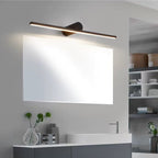 This Clérachic wall light glows above a bathroom mirror and sink holding a vase of greenery.