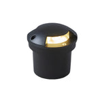 Round in-ground deck light on white, its domed black cap shielding a single warm side aperture.