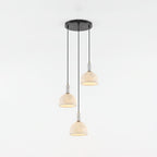 Three alabaster domes of this Clérachic pendant hang unlit at staggered heights from a shared round black ceiling plate.