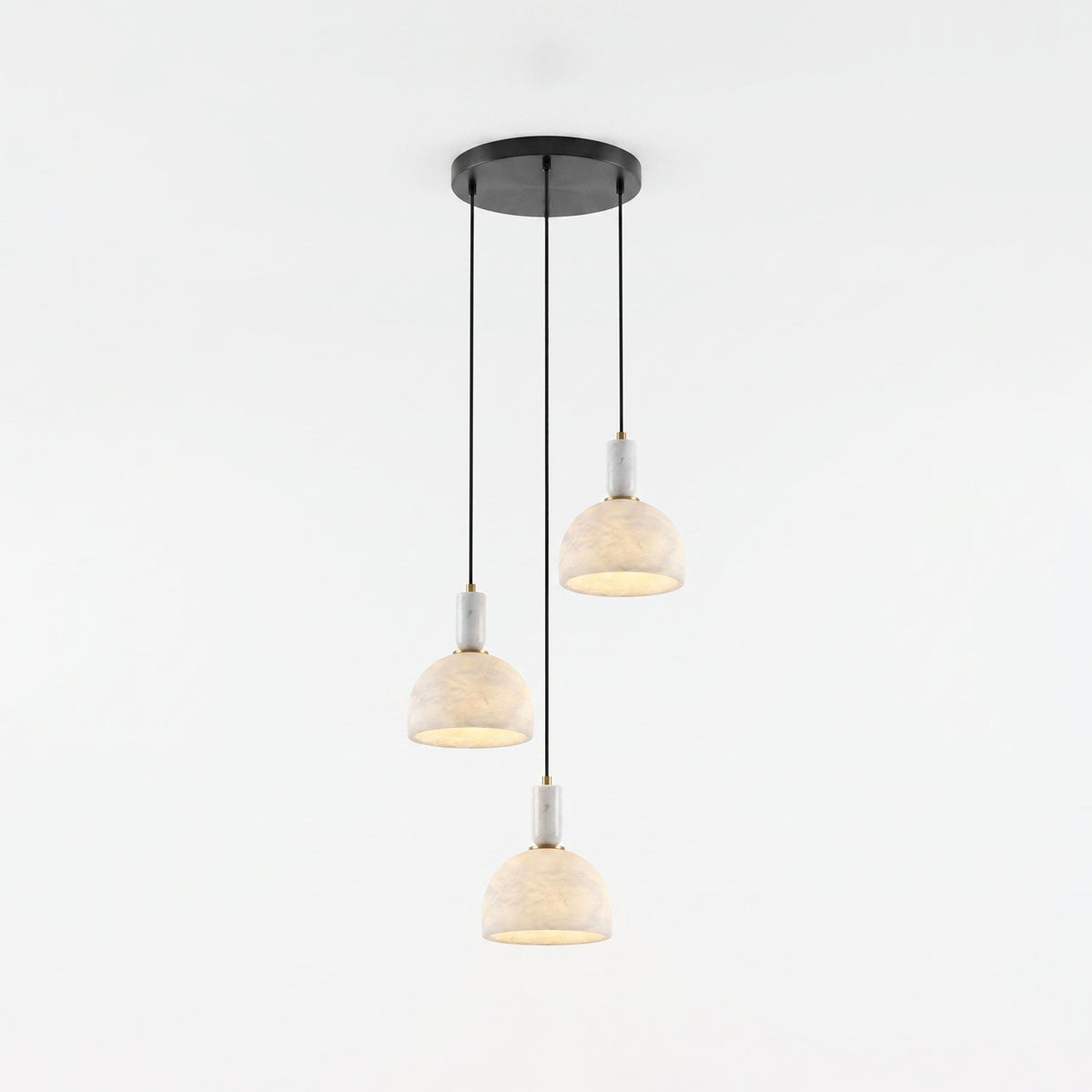 Three alabaster domes of this Clérachic pendant hang unlit at staggered heights from a shared round black ceiling plate.
