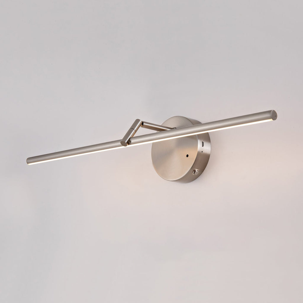 This nickel-finish Clérachic wall light glows above a two-door mirrored cabinet with open shelving and a small plant beside it.