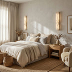 White alabaster wall light casting a warm glow on a textured wall
