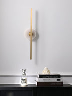 Clérachic wall sconce above a dark wooden console table holding books, a small figurine and a glowing candle.