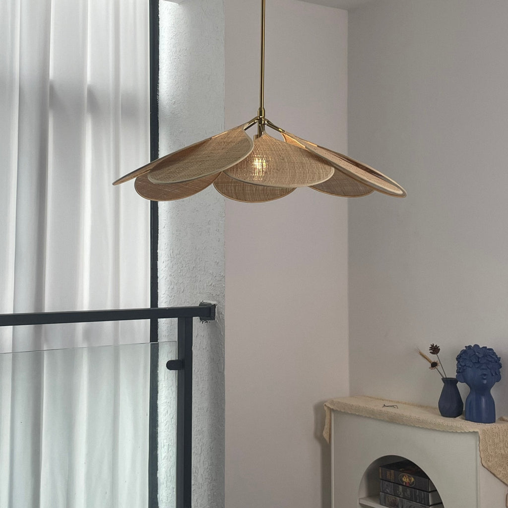This Clérachic pendant lamp in a natural woven rattan finish hangs beside tall curtained windows and a dark metal rail.