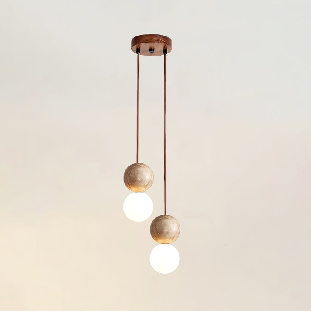Two cords drop travertine and glass spheres at differing heights from this Clérachic pendant's round canopy, studio shot.