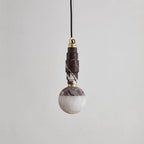 Burgundy marble version of the pendant lamp, its stacked stone stem meeting a creamy alabaster globe.