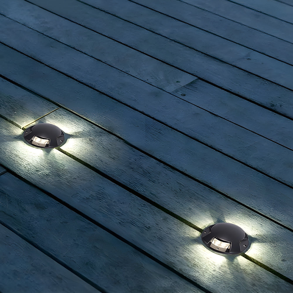 Two deck lights throwing cool white light across grey timber decking at night.