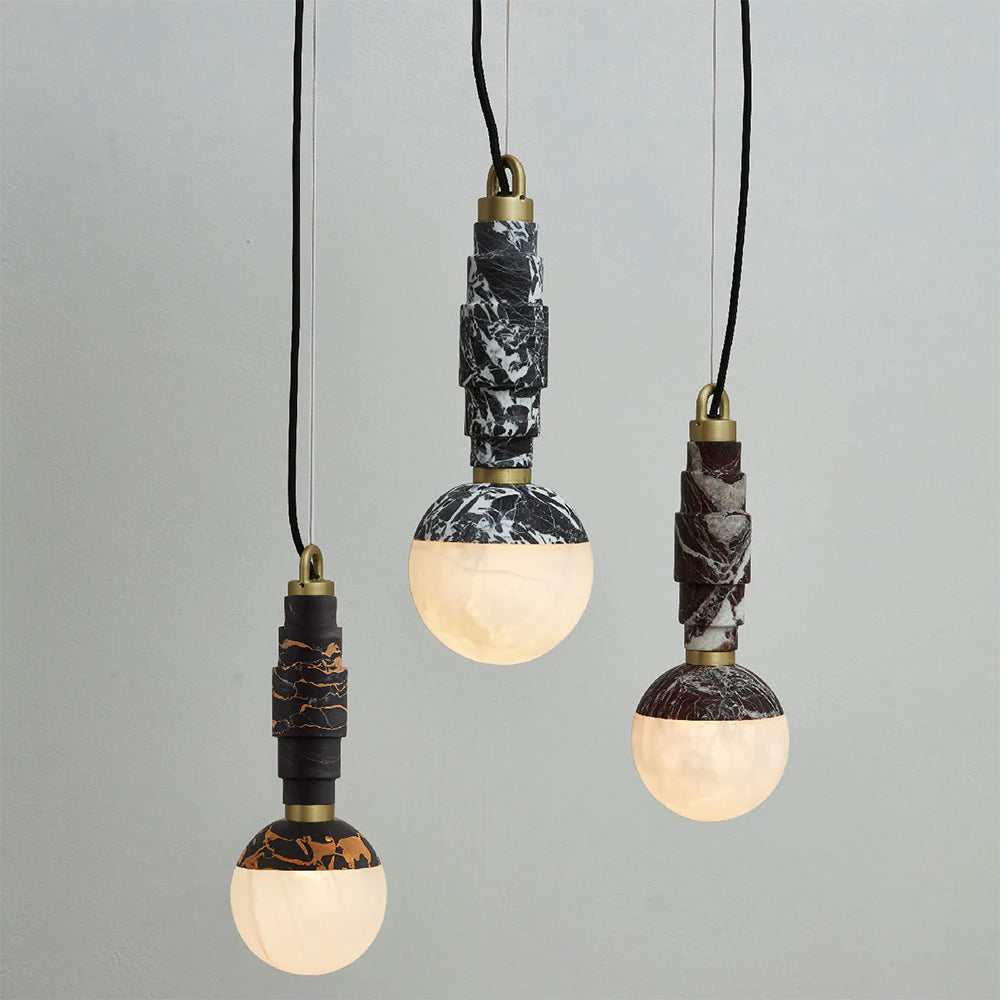 Three lit pendants hung at staggered heights in the black-and-gold, black-and-white and burgundy stone.