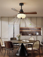 A tighter crop shows this Clérachic ceiling fan's lantern shade lit above a cone-based dining table with a flower vase and cane chairs.