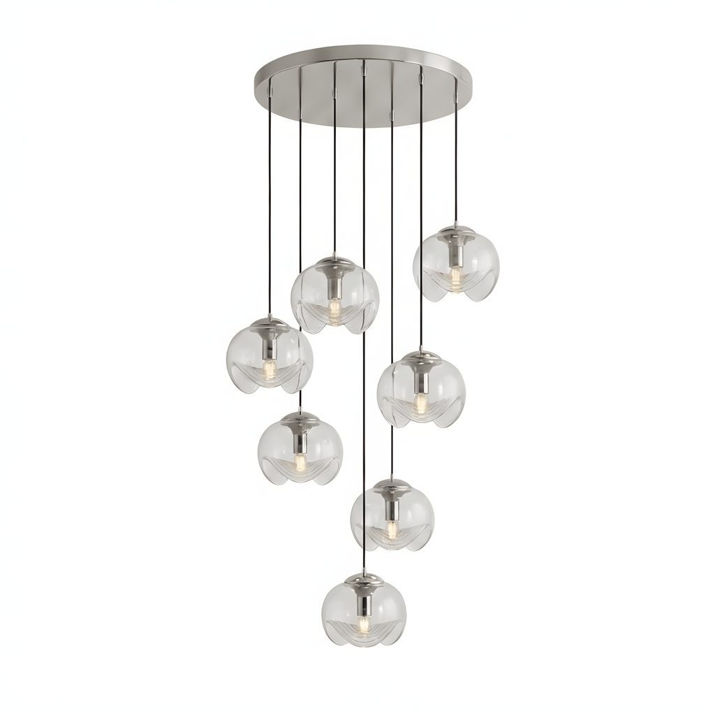 Round clear glass shades hang at varied heights from a silver ceiling plate, this Clérachic fixture shown on a white background.
