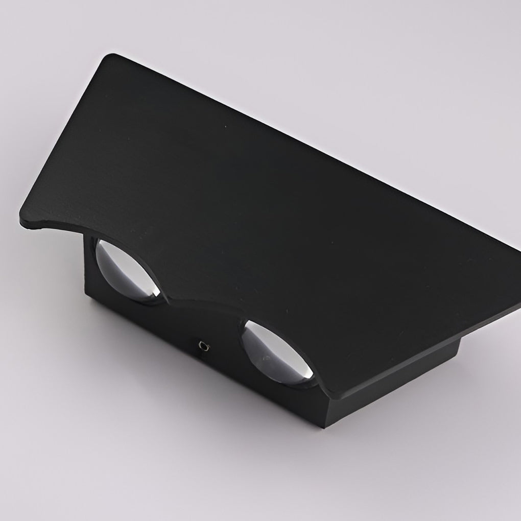 Angled studio view of the unlit sconce on grey, showing the two oval lenses set into its underside.