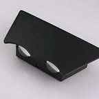Angled studio view of the unlit sconce on grey, showing the two oval lenses set into its underside.