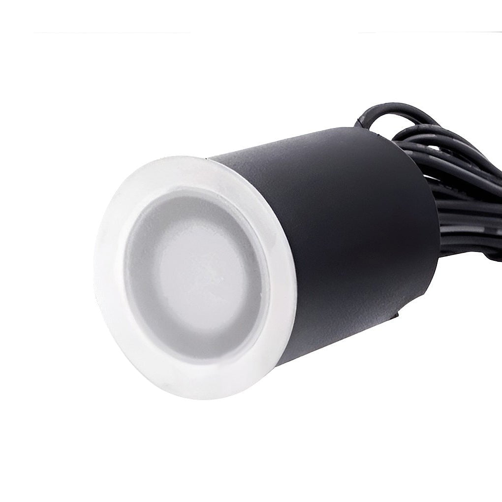 Close view of a single unlit step light, its frosted lens set in a steel ring above the black body and cable.