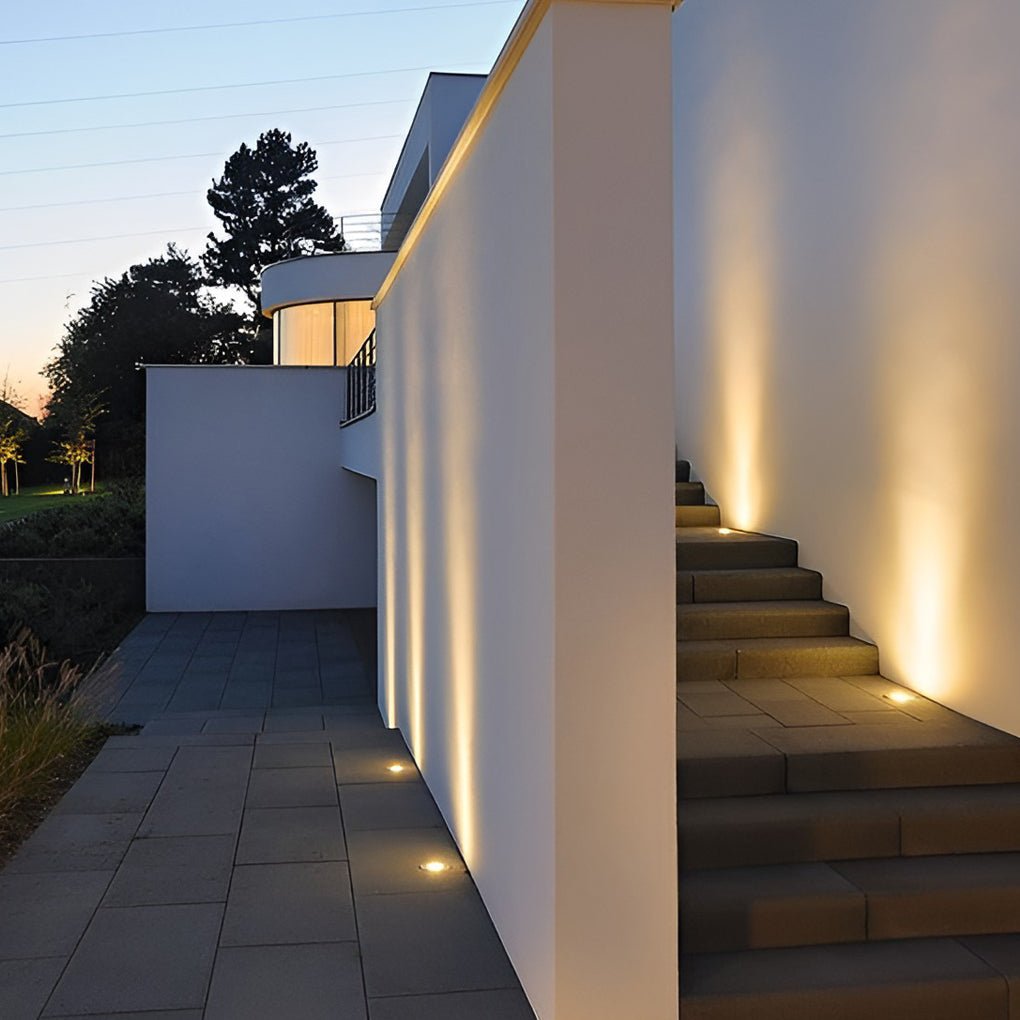 Inground lights washing a white exterior wall and stone garden steps with warm light at dusk.