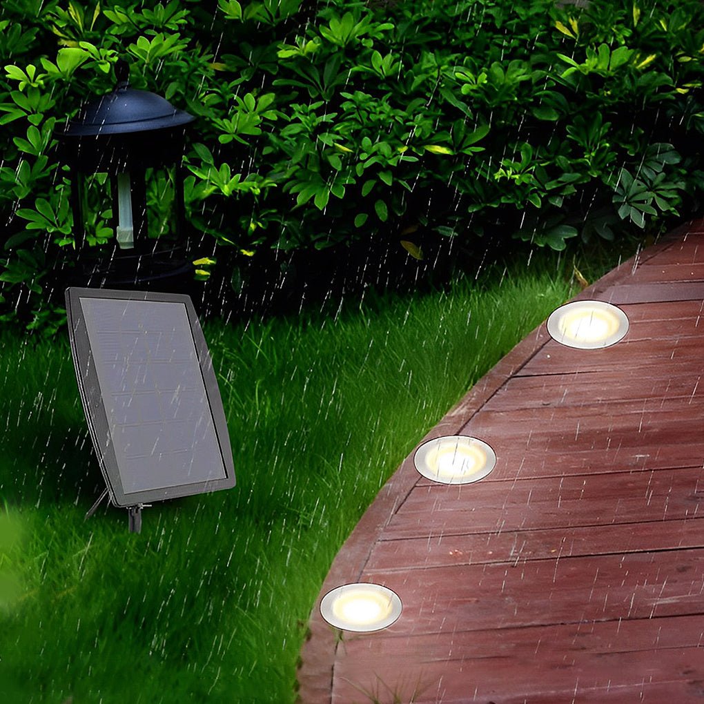 The lights lit in a timber boardwalk during rain, with the separate solar panel staked in the grass.