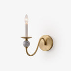 Against a white backdrop, this Clérachic wall light shows its brass S-curve arm and the marble ball beneath the candle.