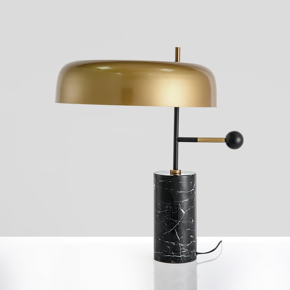This angle catches a bright reflection across the Clérachic lamp's glossy gold dome shade on a white background.