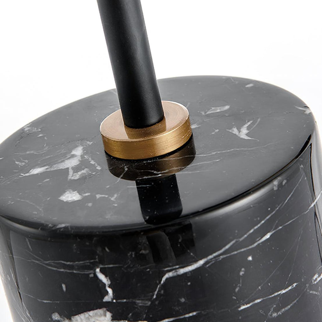 Macro shot of the Clérachic lamp's black marble base top, where a brass collar secures the black stem in place.