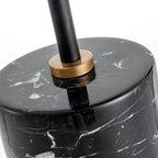 Macro shot of the Clérachic lamp's black marble base top, where a brass collar secures the black stem in place.