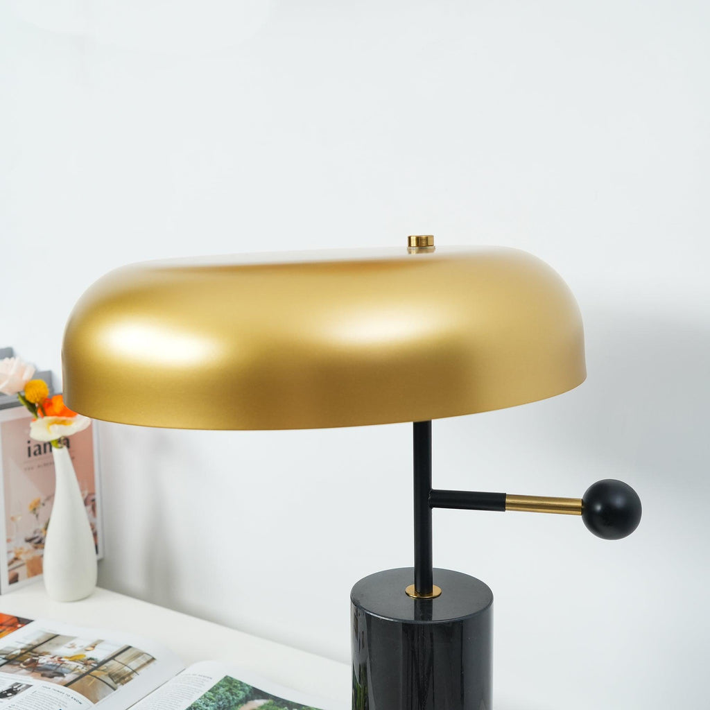 A closer angle on the Clérachic lamp shows the curved edge of its brushed gold shade against a plain grey wall.