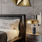 In a dark bedroom setting, the Clérachic lamp lights a nightstand next to a leather headboard and beige linens.