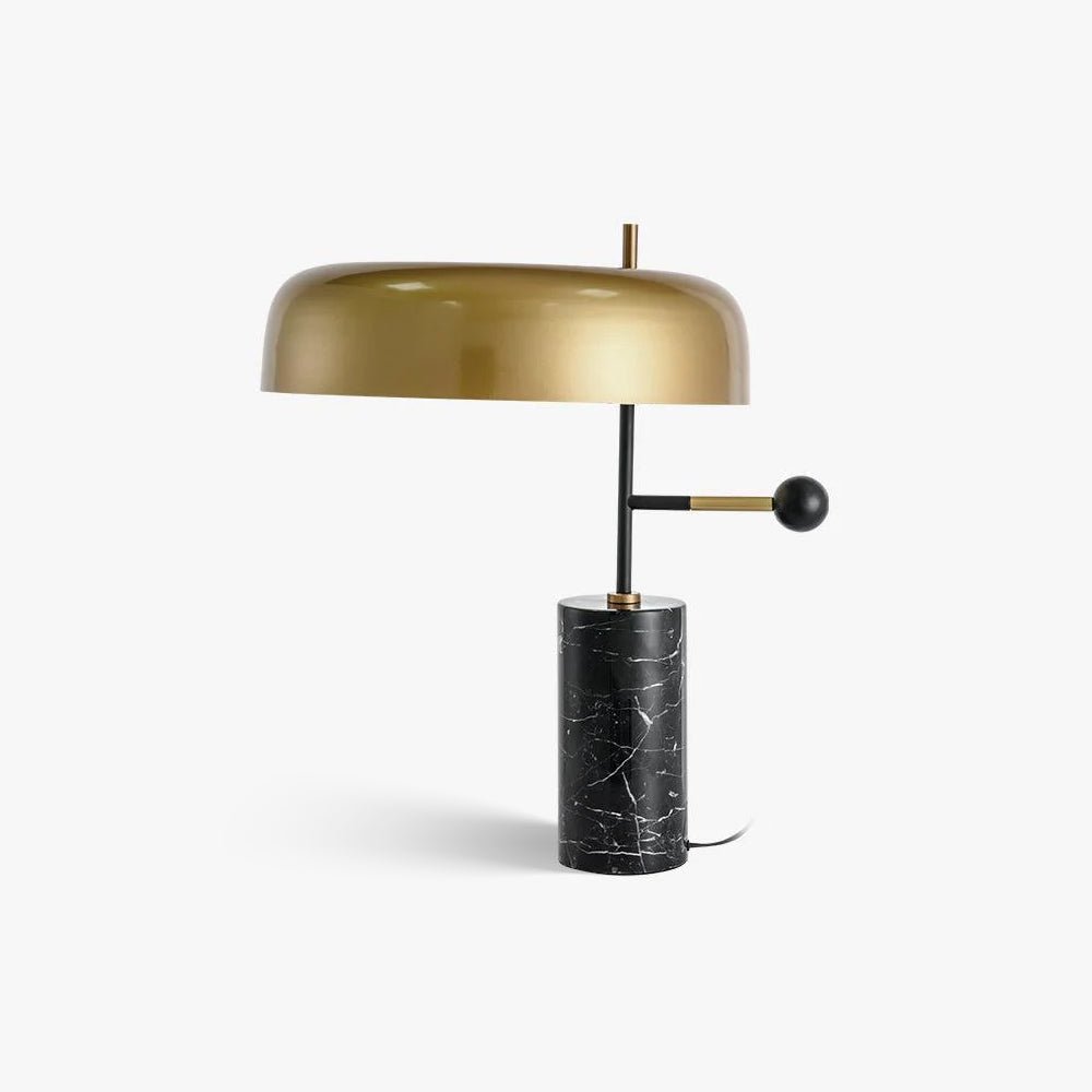 A Clérachic gold dome table lamp stands alone on white, its slim black stem and black marble base clearly shown.