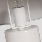 Extreme close-up of the exposed filament bulb fitted into a Clérachic table lamp's bracket, above its white marble column.