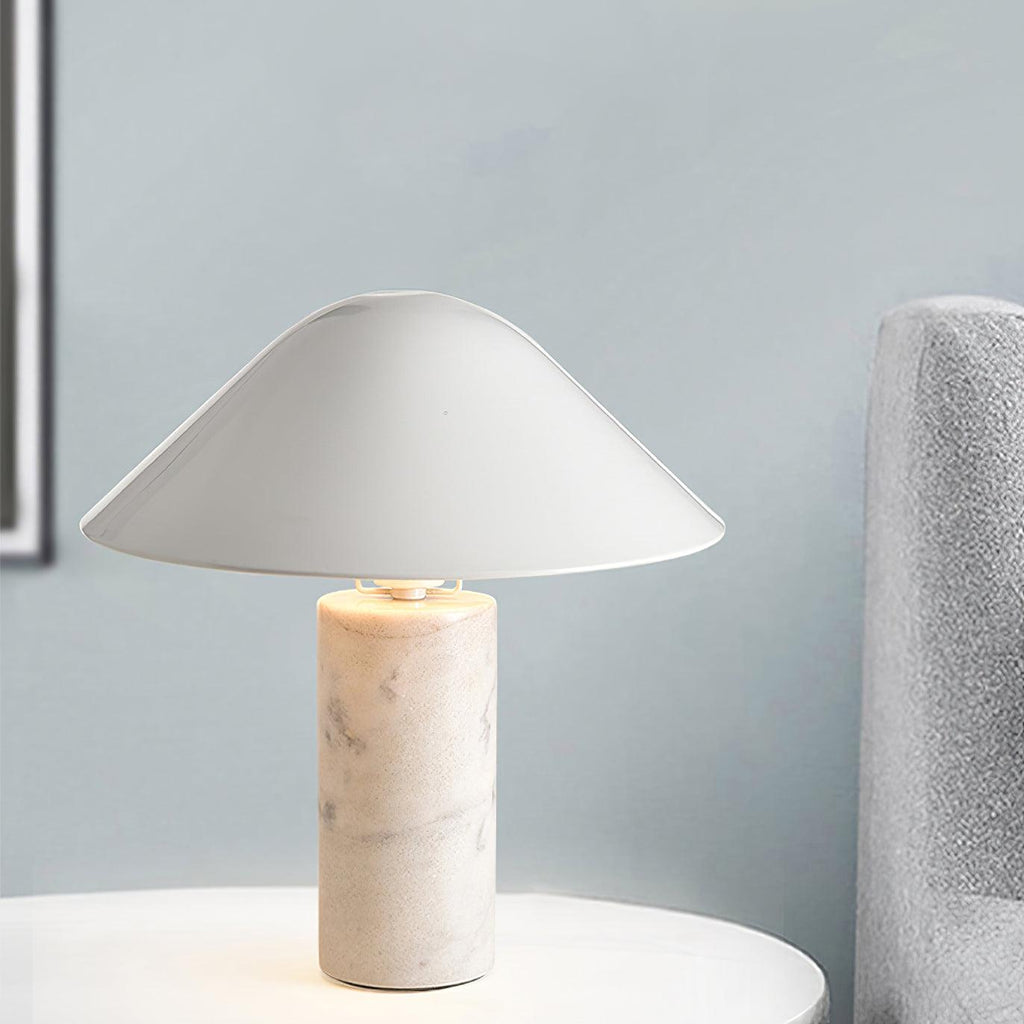 Seen against a pale blue wall and textured grey column, a Clérachic white marble table lamp lights a round side table.