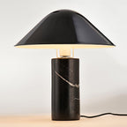 Warm cream studio light surrounds this Clérachic black marble table lamp, its cord trailing to one side.