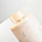Tighter close-up of the same Clérachic lamp's bracket and glowing bulb, showing the grey veining of its marble column.