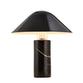 Seen straight-on against a plain white studio background, a Clérachic black marble table lamp stands lit and centred.