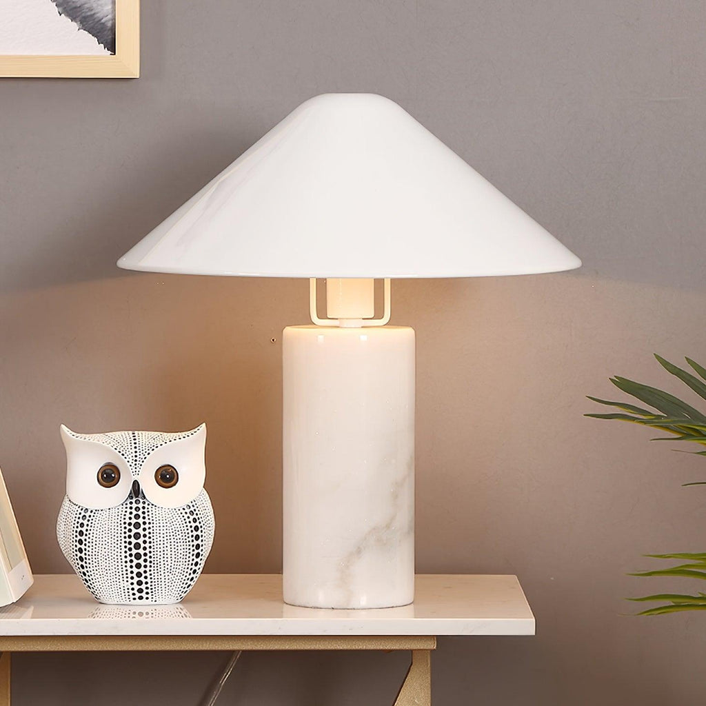 Clérachic white marble table lamp lit on a console table beside a patterned ceramic owl and trailing plant leaves.