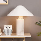 Clérachic white marble table lamp lit on a console table beside a patterned ceramic owl and trailing plant leaves.