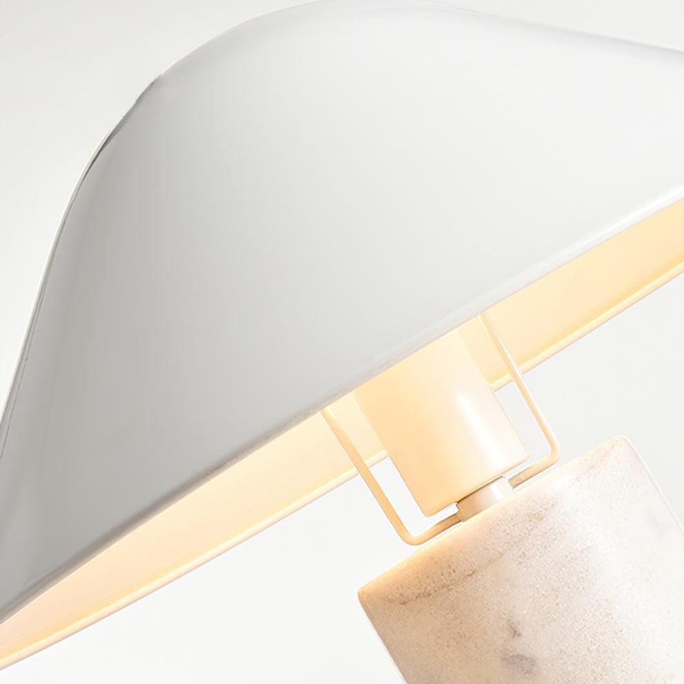 Close-up of the metal bracket joining a Clérachic white shade to its marble column, the bulb glowing at the joint.