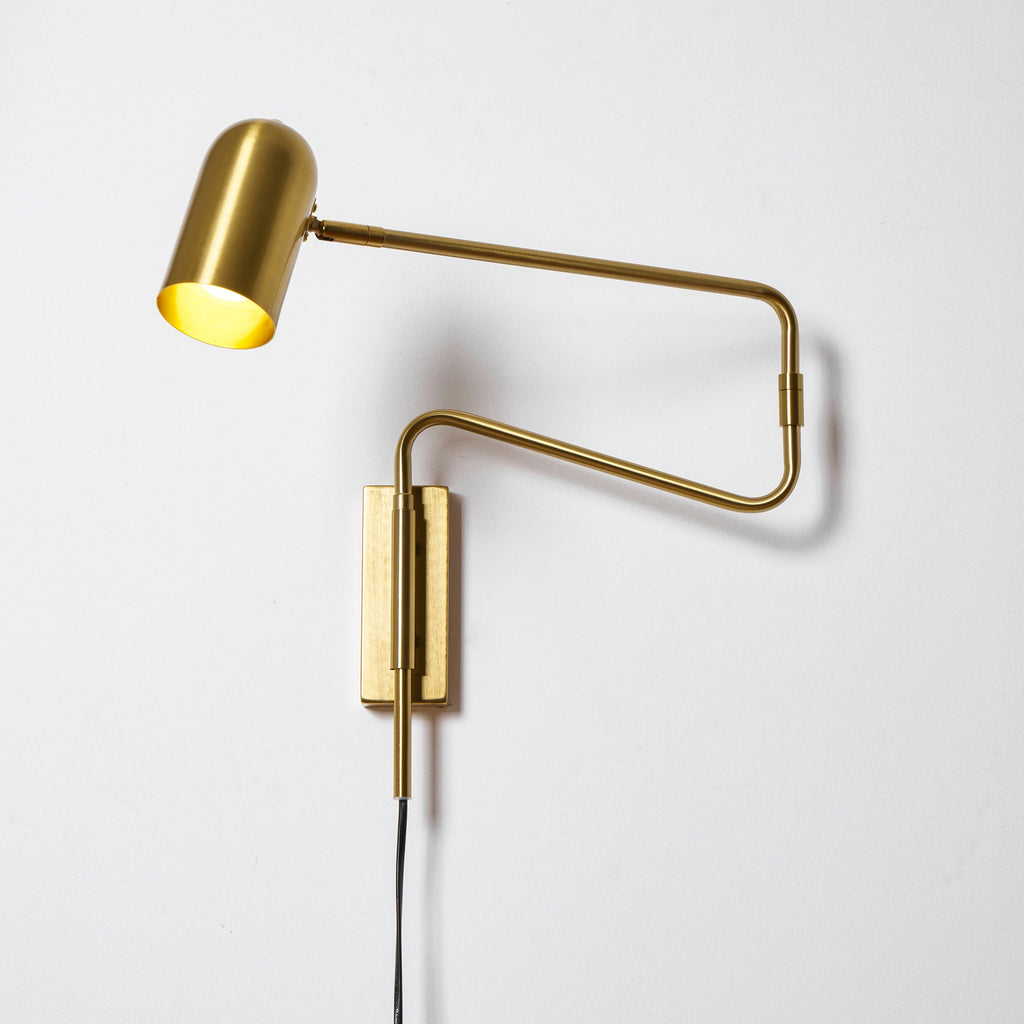 Swing arm wall lamp shown lit in a cozy interior