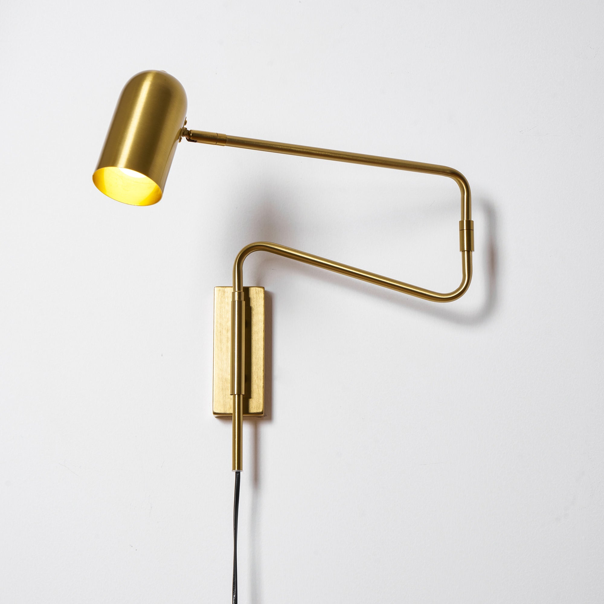 Swing arm wall lamp shown lit in a cozy interior
