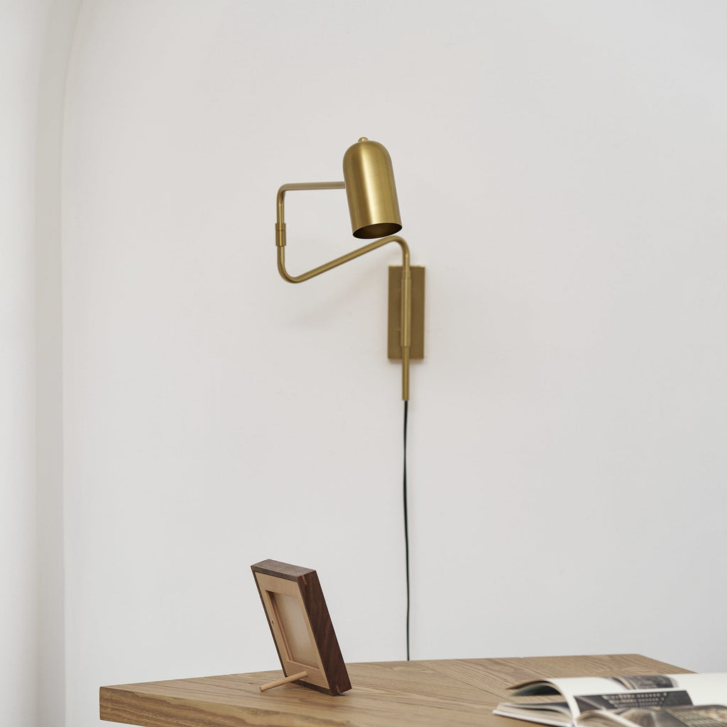 Swing arm wall lamp shown lit over a bedside setting