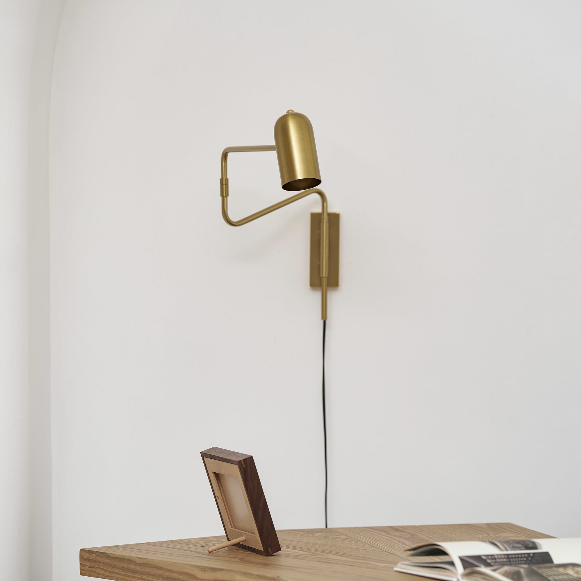 Swing arm wall lamp shown lit over a bedside setting