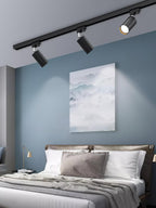 Track ceiling light spotlights angled across a textured wall