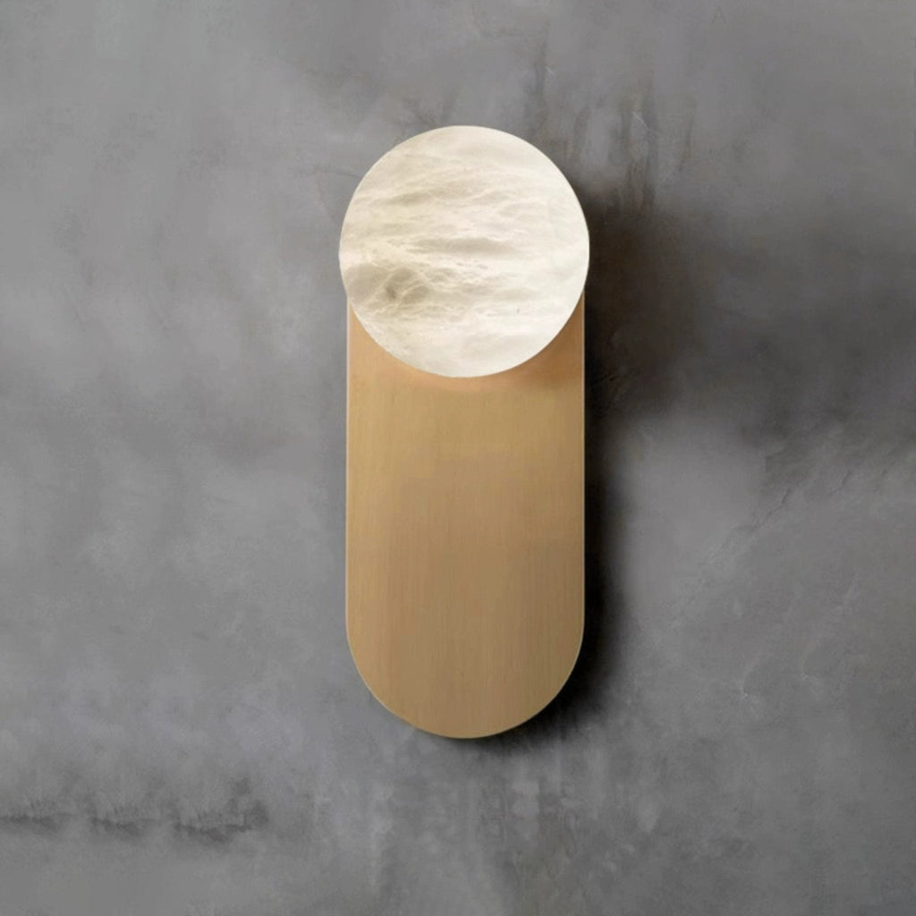 Straight-on view of the Adela sconce on grey concrete, veining visible across the hand-carved alabaster disc