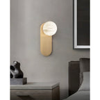 Adela wall sconce above a bedside table in a grey bedroom, hung next to a large framed artwork