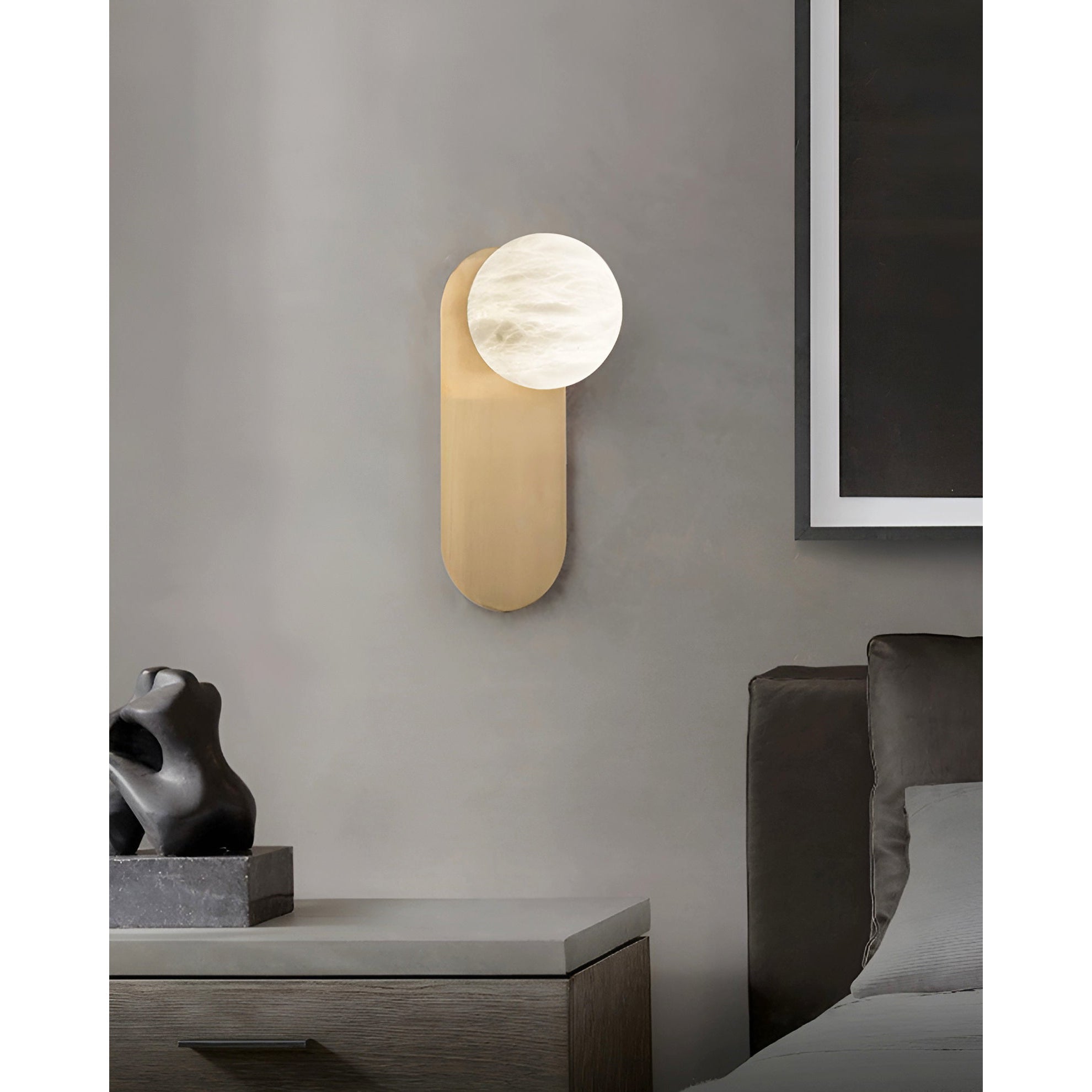 Adela wall sconce above a bedside table in a grey bedroom, hung next to a large framed artwork
