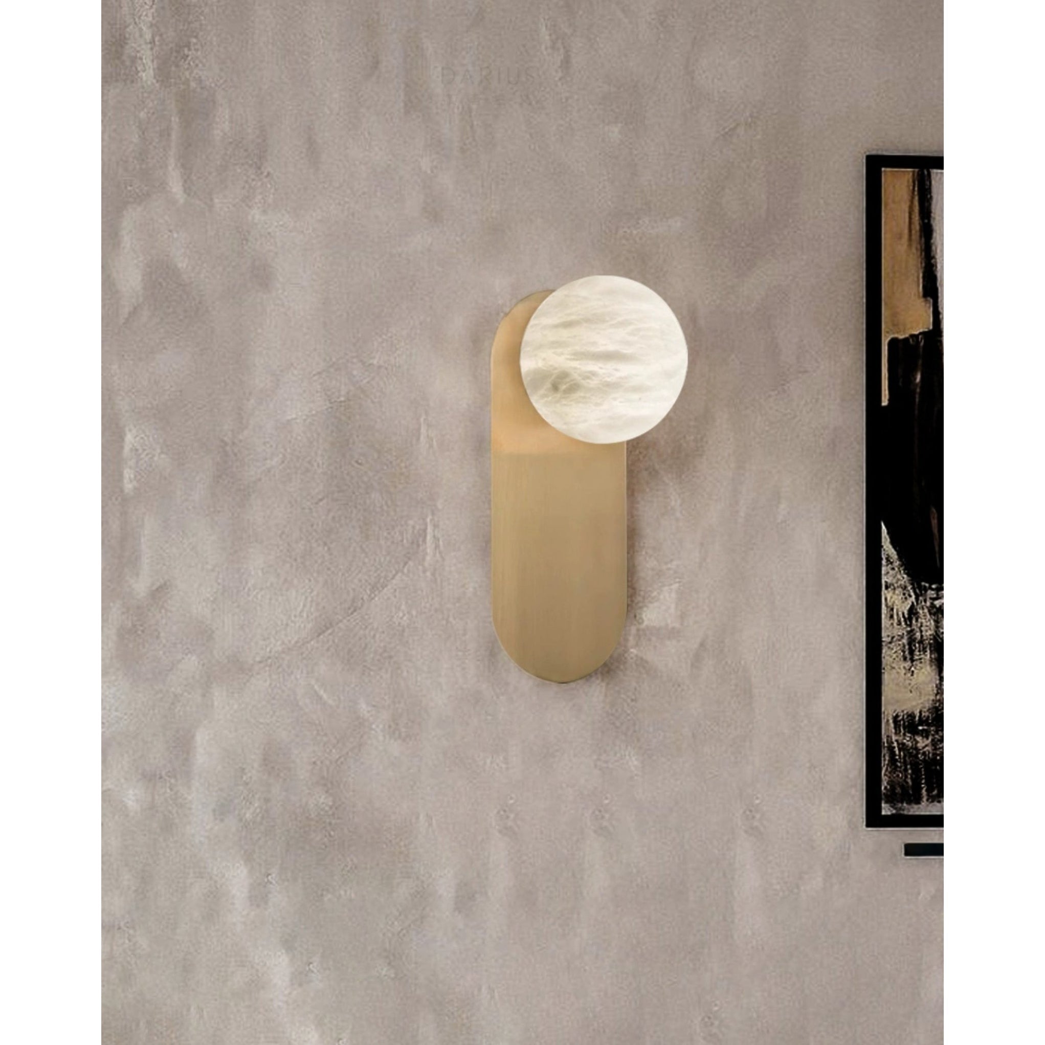 Adela wall sconce on a textured plaster wall beside a black and white abstract painting
