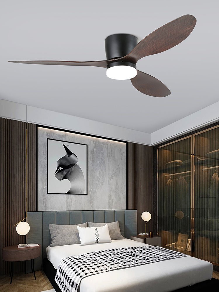 This Clérachic ceiling fan glows warm above a bedroom with a dark wood accent wall and framed abstract art.