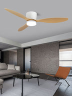 Light wood-grain blades turn on this Clérachic ceiling fan, glowing warm above a living room with a dark stone wall and a rust-orange chair.