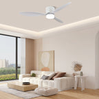 Wide white blades spin on this Clérachic ceiling fan, glowing warm along a crown-lit ceiling above a cream sofa and city view.