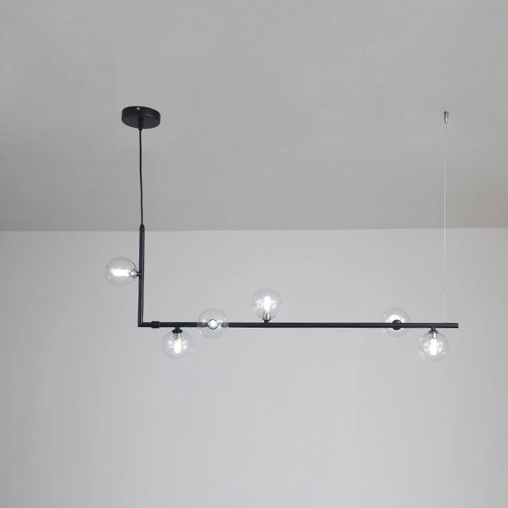 Clear glass sphere pendant light glowing above a dining table